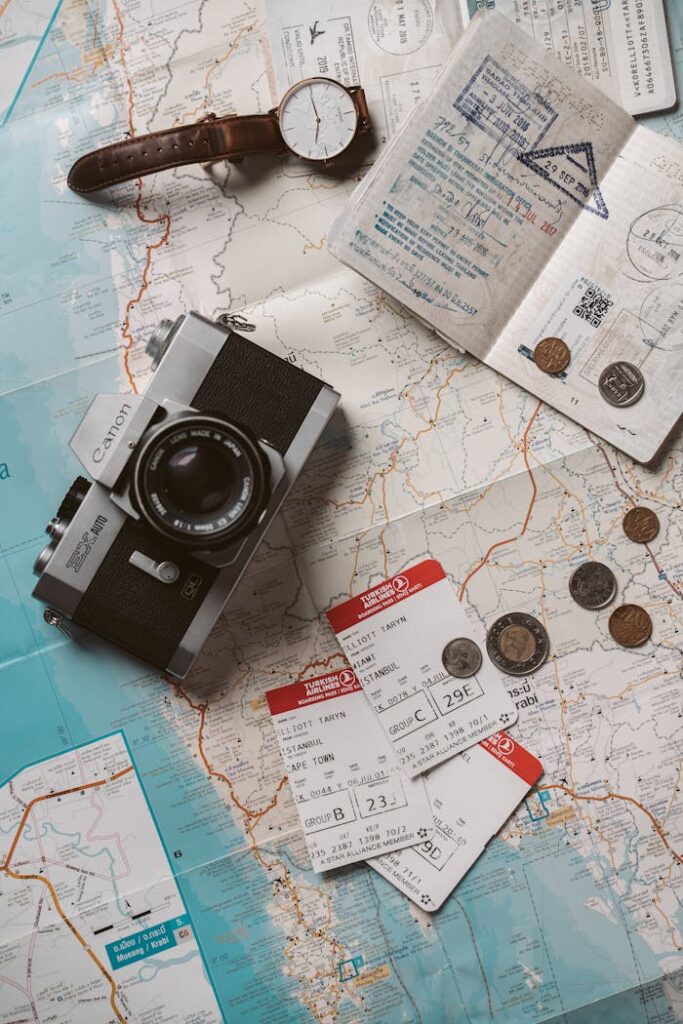 Flat lay travel essentials including passports, tickets, and a vintage camera on a world map.